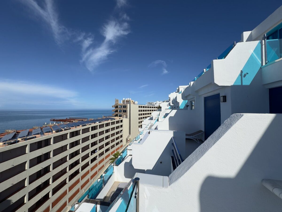 White modern apartments overlooking the ocean under a clear blue sky in Gran Canaria.