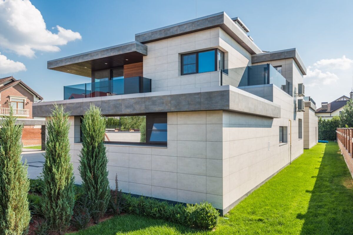 Contemporary two-story house with clean lines surrounded by green grass and blue sky.